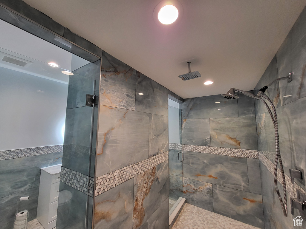 Bathroom featuring tile walls, a stall shower, and recessed lighting