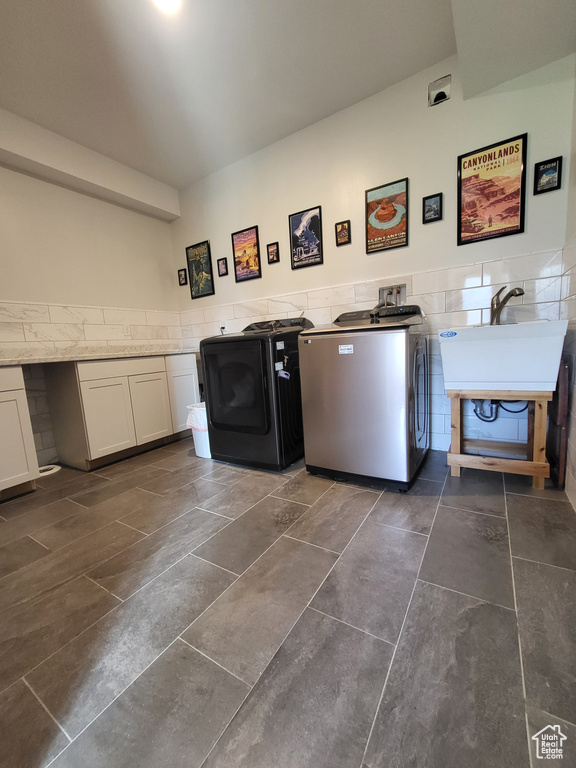 Laundry area with washer / clothes dryer, tile walls, a wainscoted wall, and dark tile patterned floors