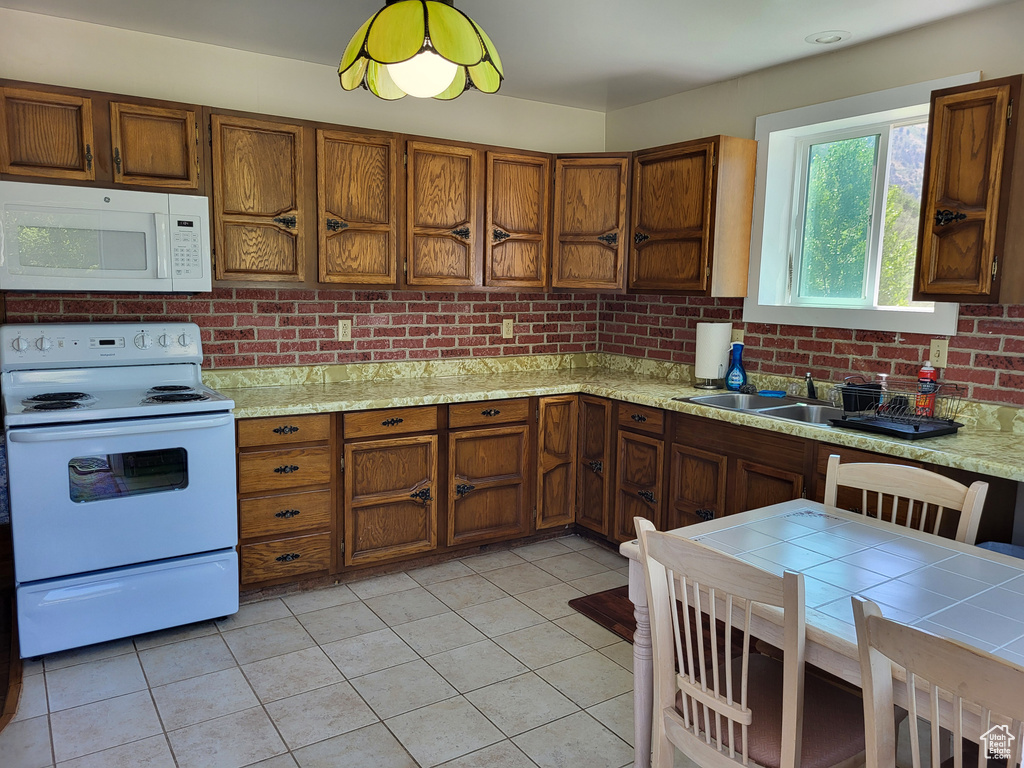 Kitchen featuring white appliances, light countertops, and brown cabinetry