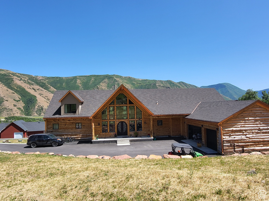 Back of house with a mountain view, an attached garage, and a yard