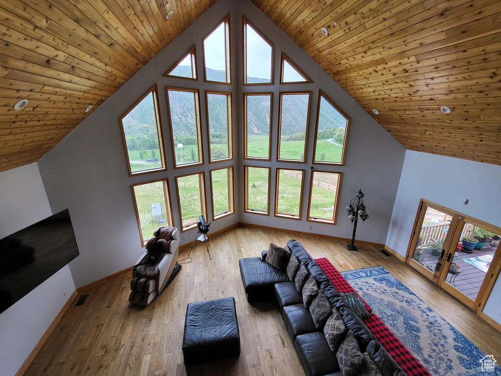 Living area with light wood finished floors, french doors, high vaulted ceiling, and wooden ceiling