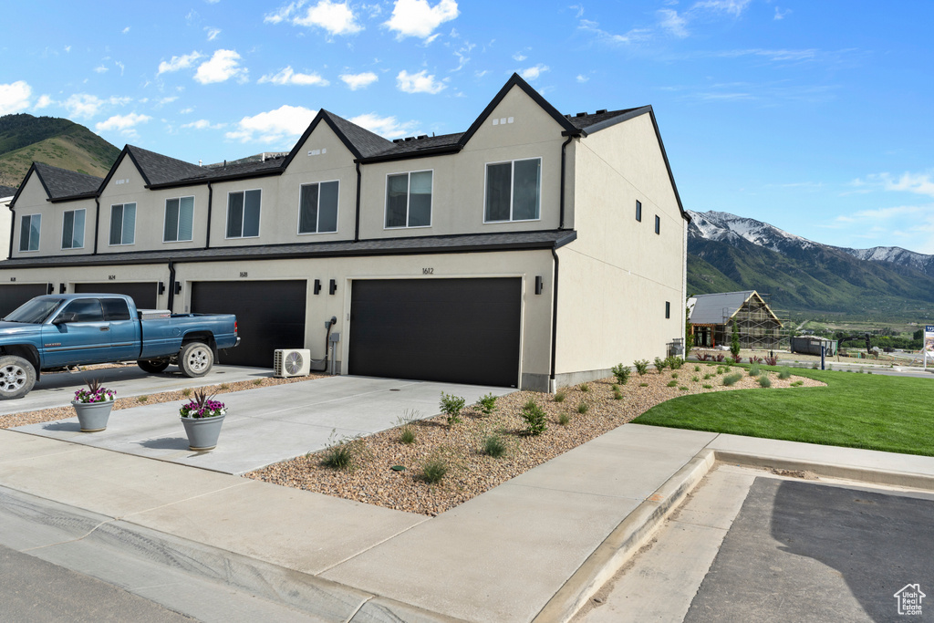 View of front of property featuring a mountain view, an attached garage, a front yard, and driveway