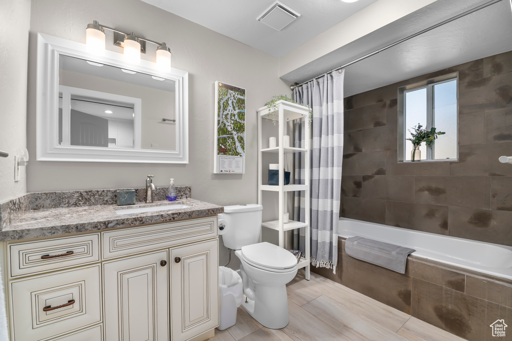 Bathroom with plenty of natural light, vanity, shower / tub combo, and wood finished floors