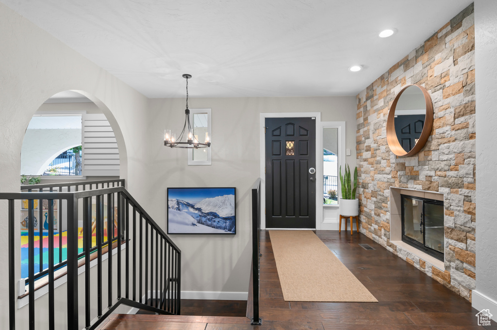 Foyer entrance featuring hardwood / wood-style flooring, a chandelier, recessed lighting, and a stone fireplace