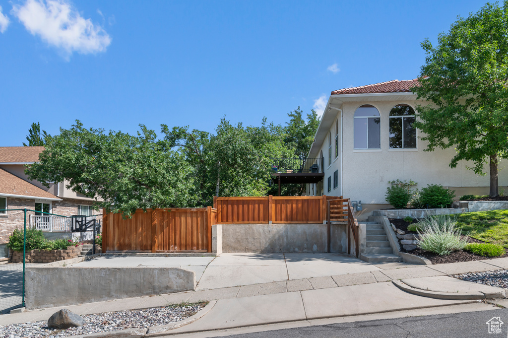 View of side of property featuring a fenced front yard, a gate, stucco siding, and a tile roof