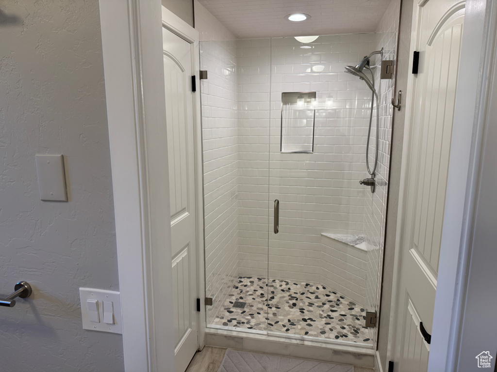 Bathroom with a shower stall, a textured wall, and recessed lighting