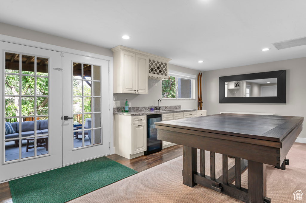 Kitchen featuring beverage cooler, recessed lighting, french doors, dark carpet, and light stone countertops