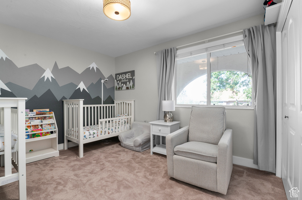 Carpeted bedroom featuring a nursery area and baseboards