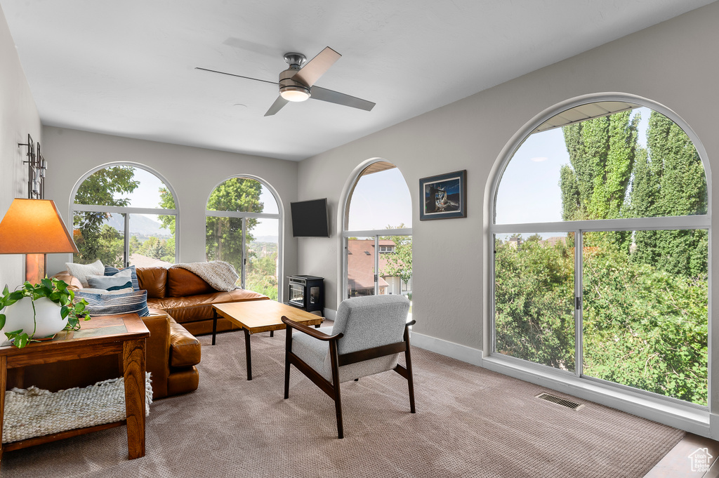 Carpeted living area featuring a ceiling fan and baseboards