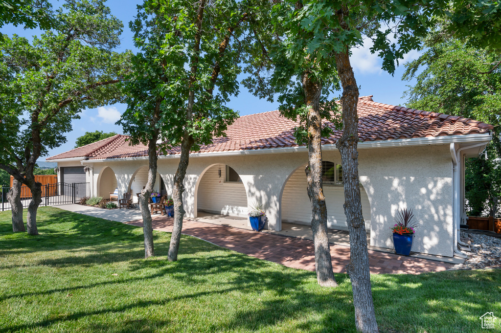 Back of house with stucco siding, a tiled roof, and a garage