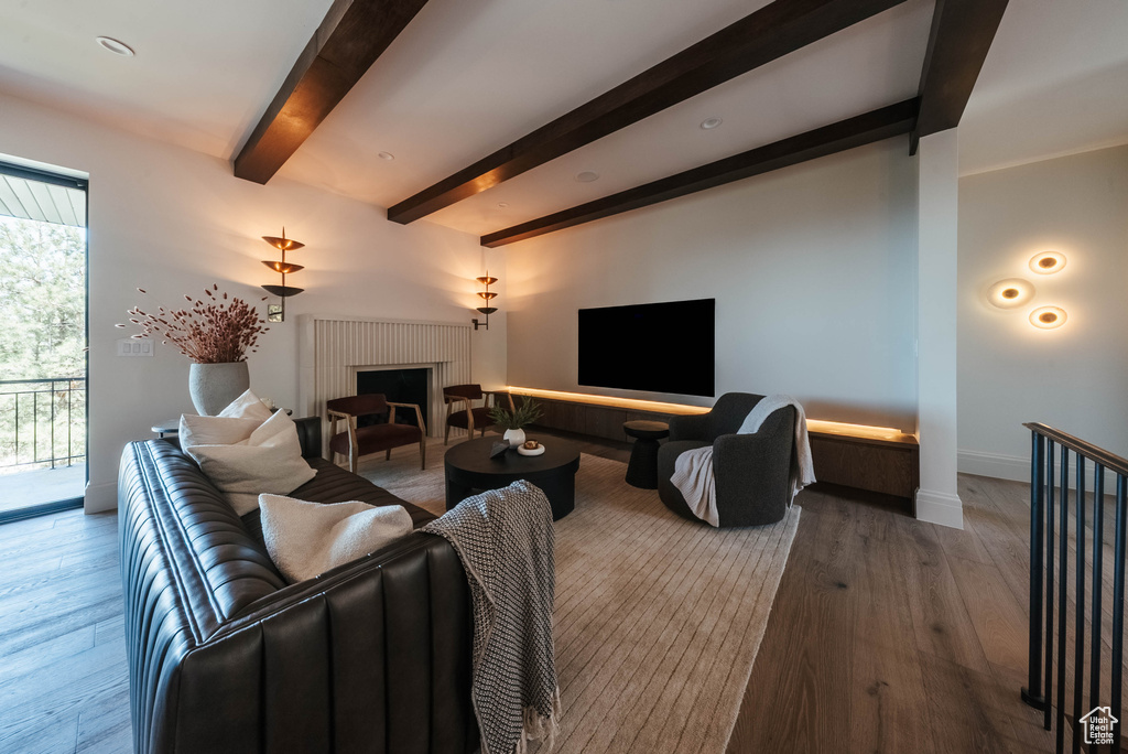 Living room with beamed ceiling, a fireplace, and wood finished floors