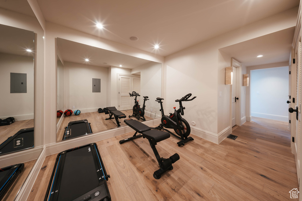 Workout area with light wood-style floors, recessed lighting, and electric panel