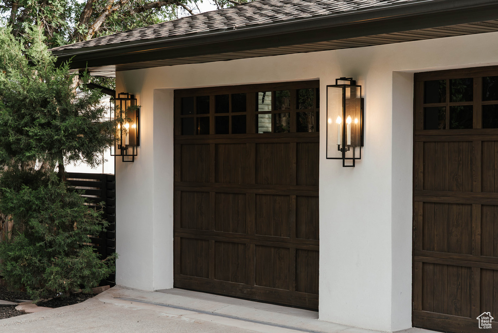 Doorway to property featuring a garage and a shingled roof