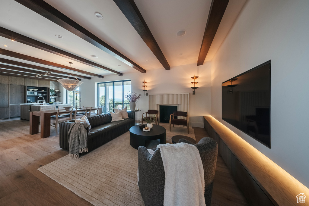 Living area with a fireplace, light wood-style flooring, and beamed ceiling