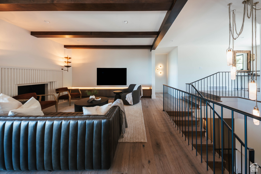 Living room with beamed ceiling, wood finished floors, and a fireplace