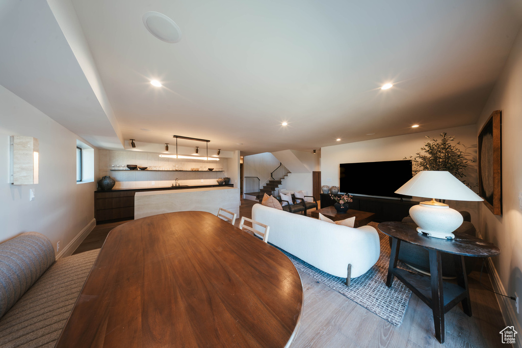 Dining space with wood finished floors, stairs, and recessed lighting