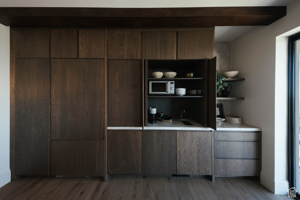 Bar featuring stainless steel microwave and wood finished floors