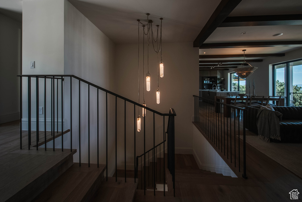 Stairway with wood finished floors and beam ceiling