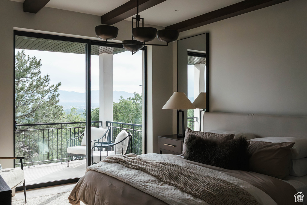 Bedroom with multiple windows, beamed ceiling, access to exterior, and a mountain view