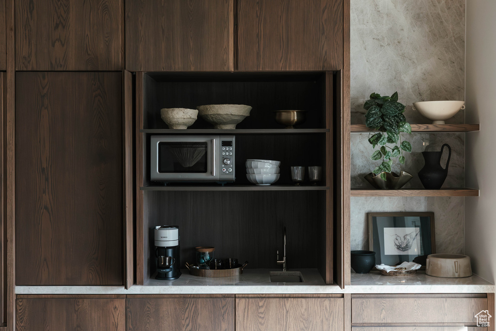 Kitchen view of stainless steel microwave, open shelves, modern cabinets, and dark brown cabinets