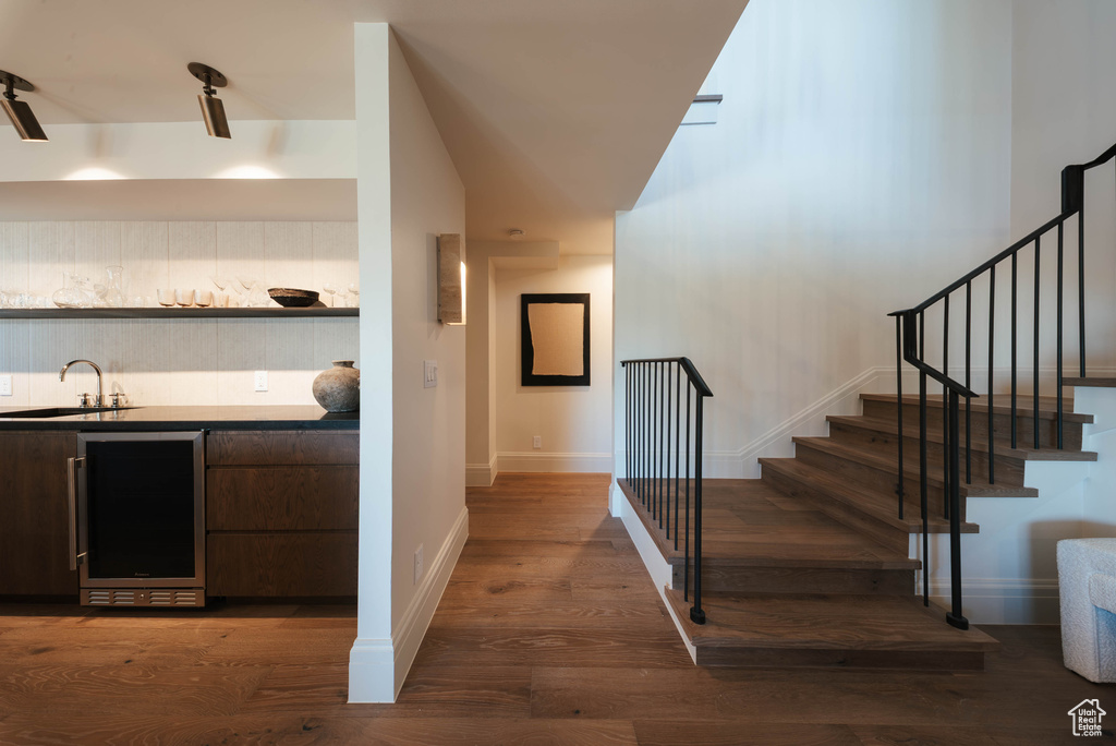 Indoor wet bar featuring wine cooler, dark wood finished floors, and stairway