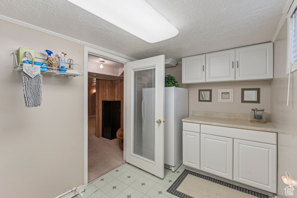 Kitchen featuring a textured ceiling, white cabinets, light countertops, and a heating unit