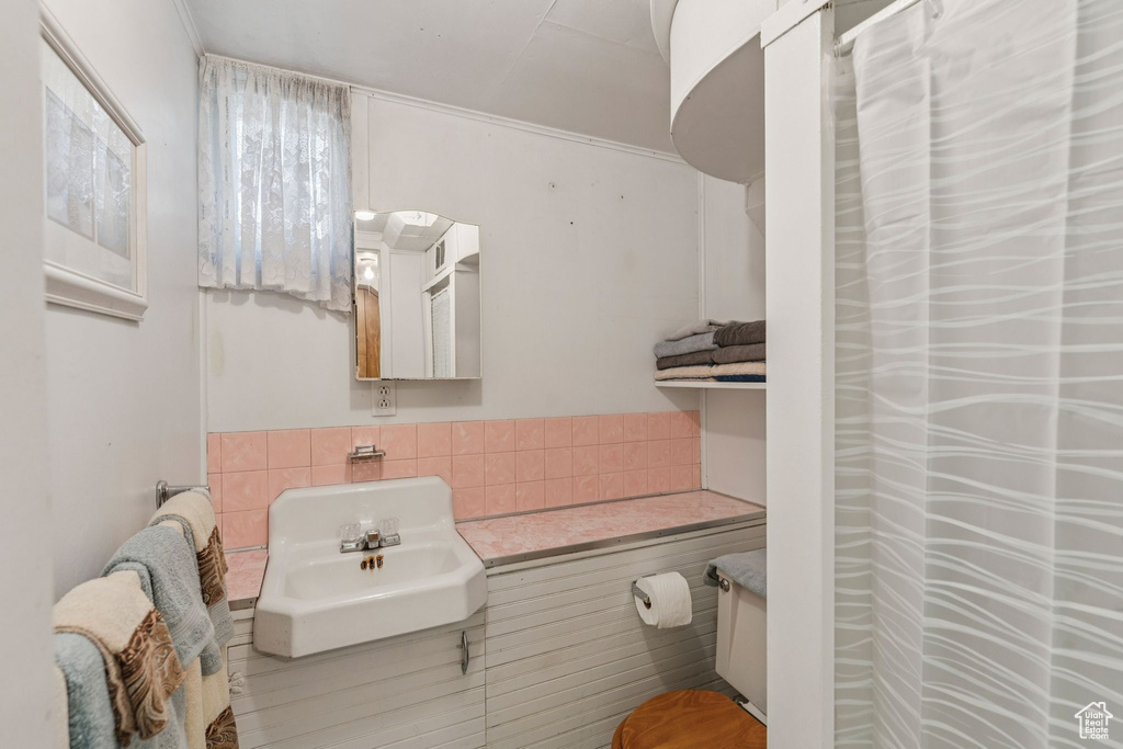 Full bathroom featuring a sink and tile walls