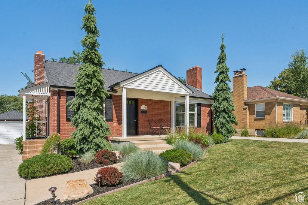 Ranch-style home featuring brick siding, a front yard, and a chimney