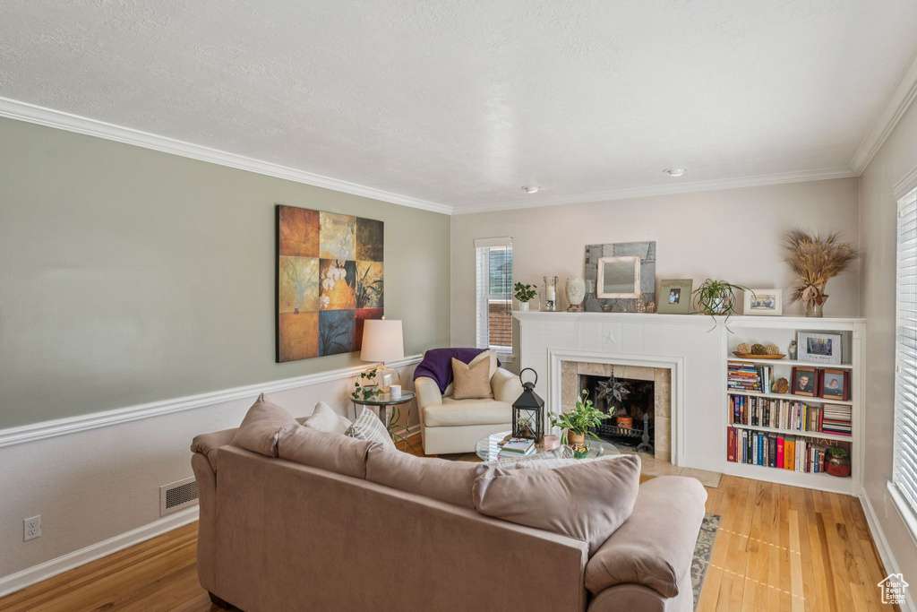 Living room featuring a fireplace, healthy amount of natural light, wood finished floors, and ornamental molding