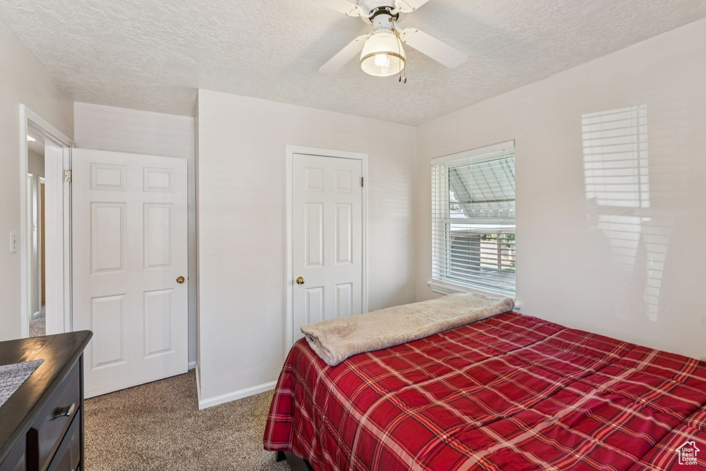 Carpeted bedroom with a textured ceiling and ceiling fan