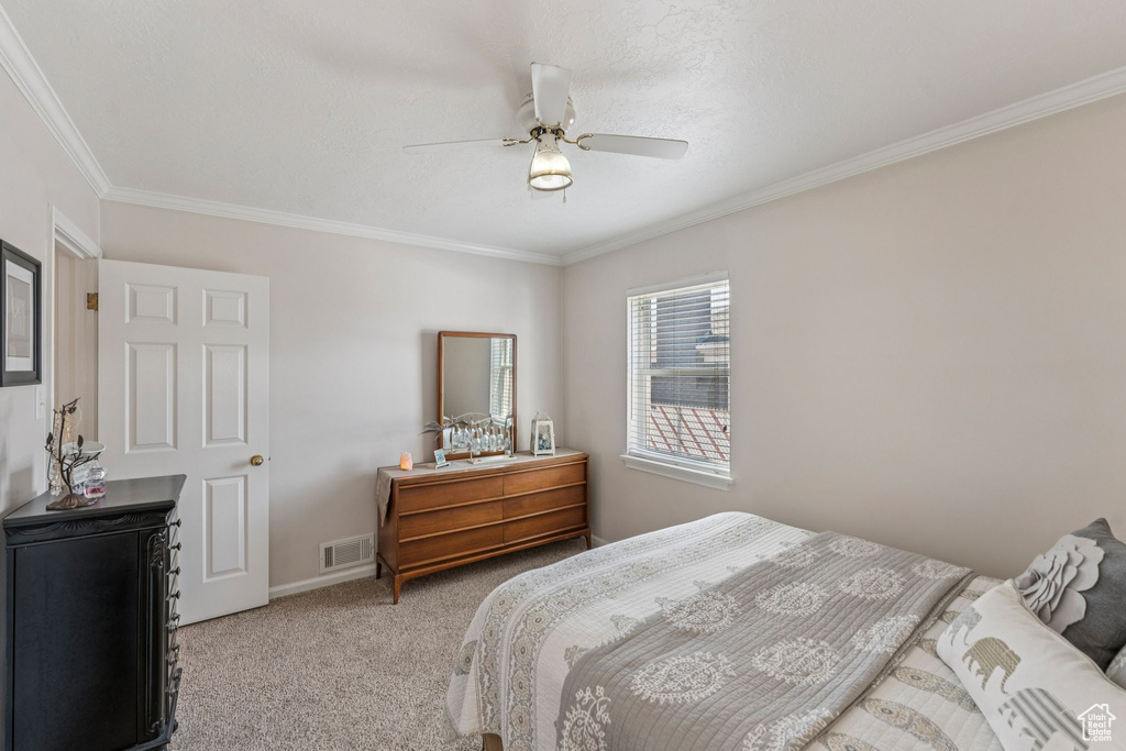 Bedroom with light colored carpet, ornamental molding, and ceiling fan