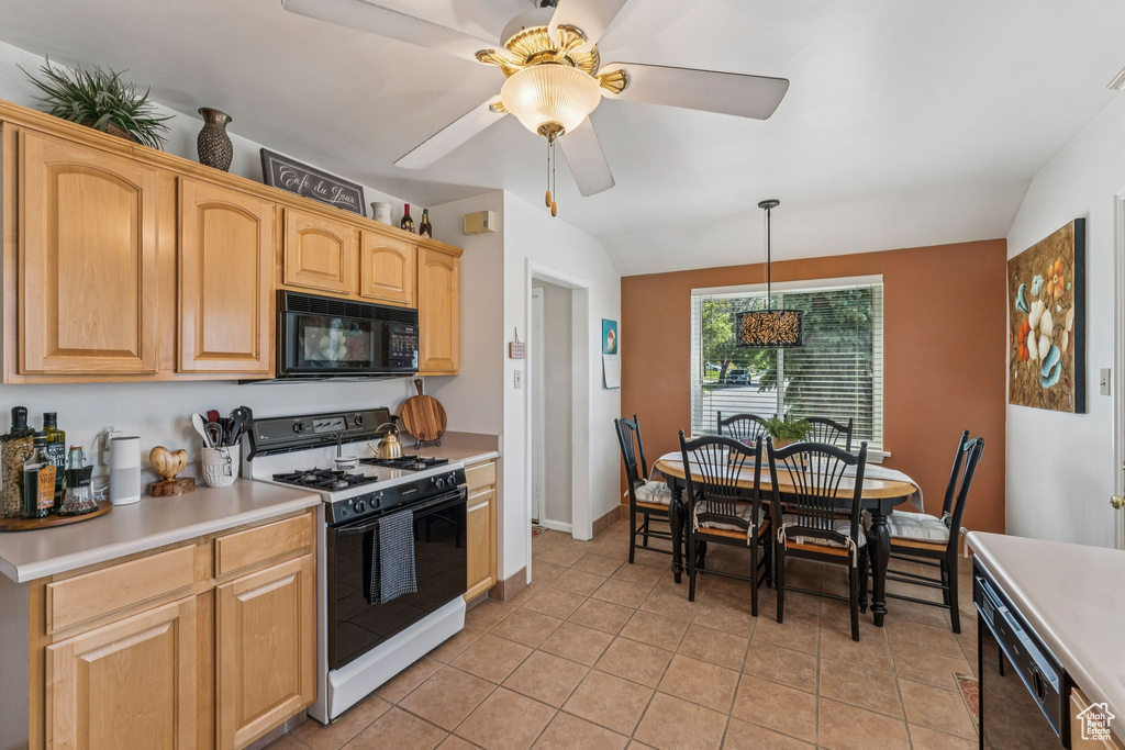 Kitchen with gas stove, black microwave, light countertops, ceiling fan, and light tile patterned floors