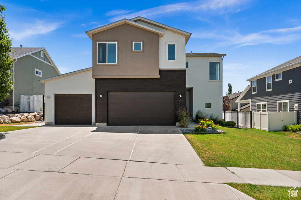 View of front facade with stucco siding, driveway, and an attached garage