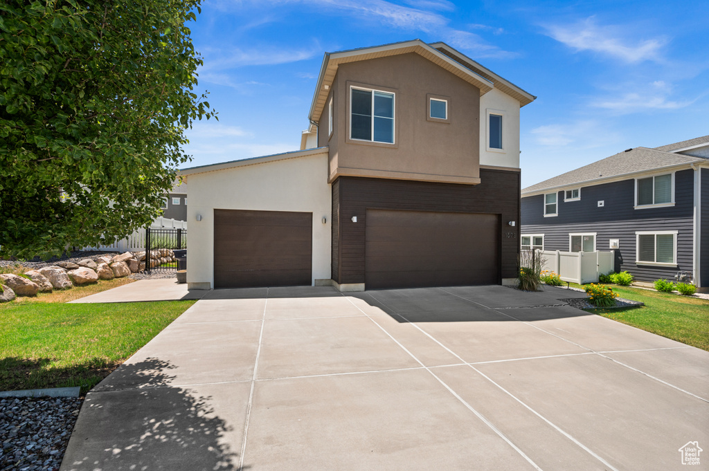 View of front facade featuring stucco siding, concrete driveway, and a garage