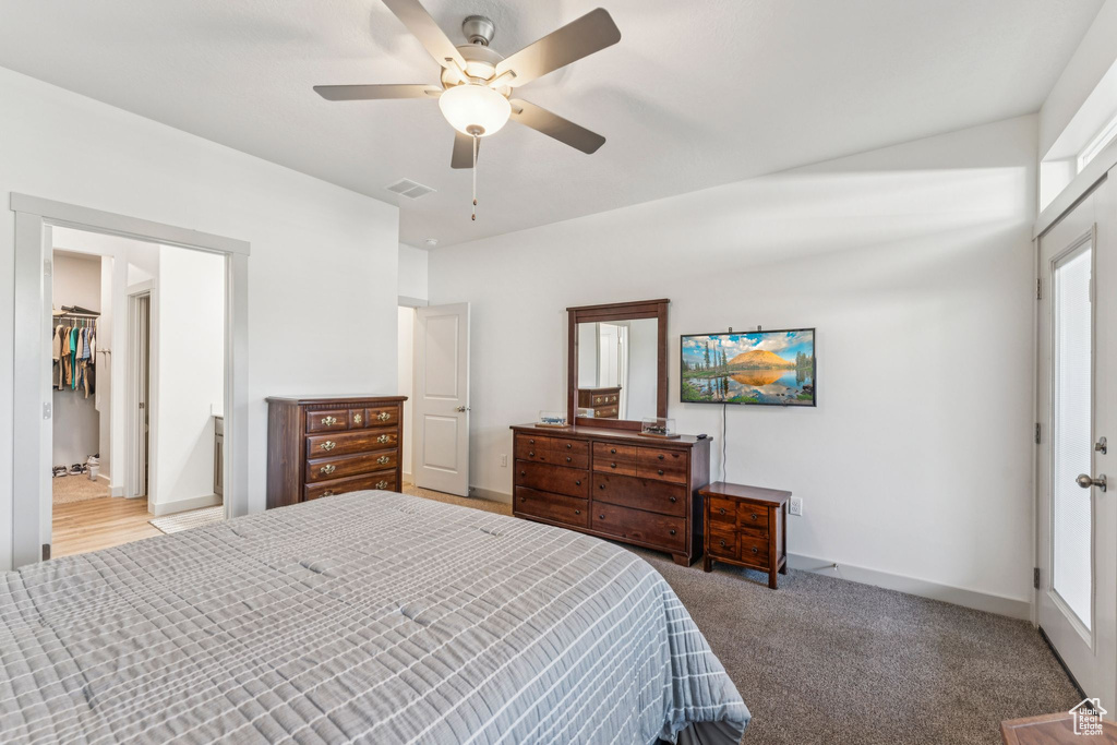 Carpeted bedroom with a ceiling fan and a walk in closet