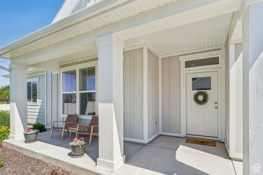 View of exterior entry with board and batten siding and covered porch