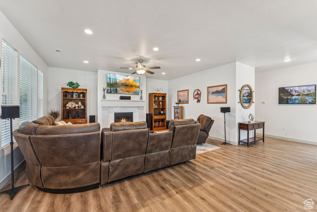Living room with wood finished floors, recessed lighting, ceiling fan, and a fireplace