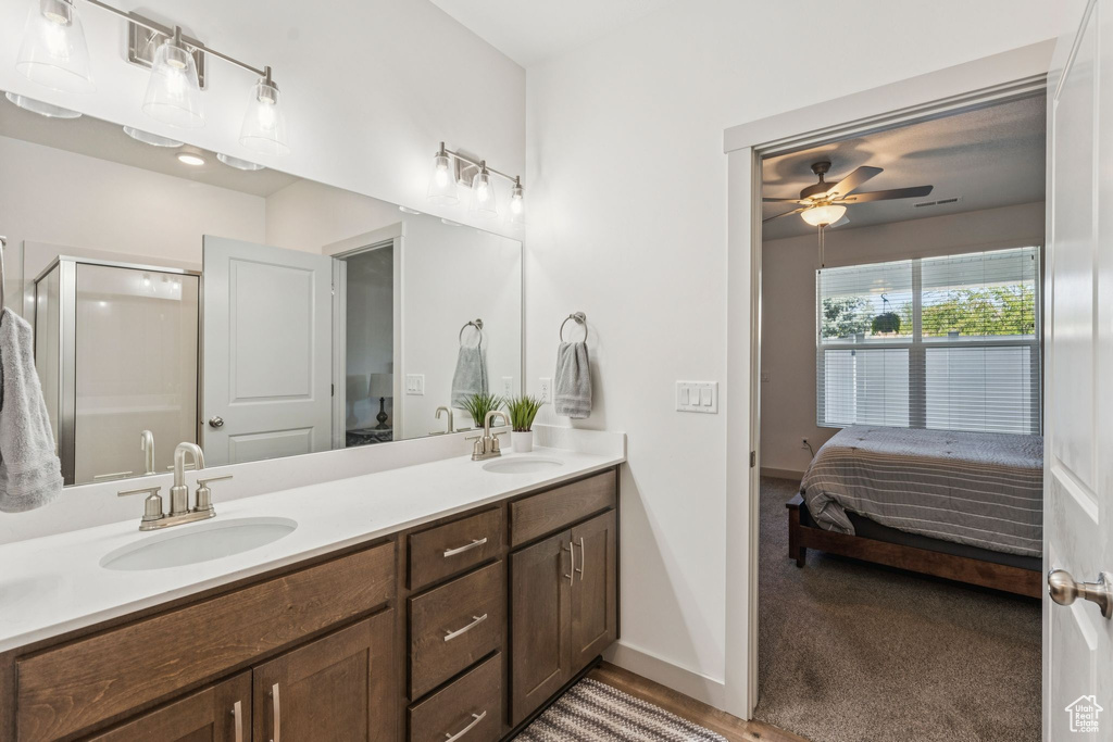 Bathroom with connected bathroom, double vanity, a ceiling fan, and a stall shower