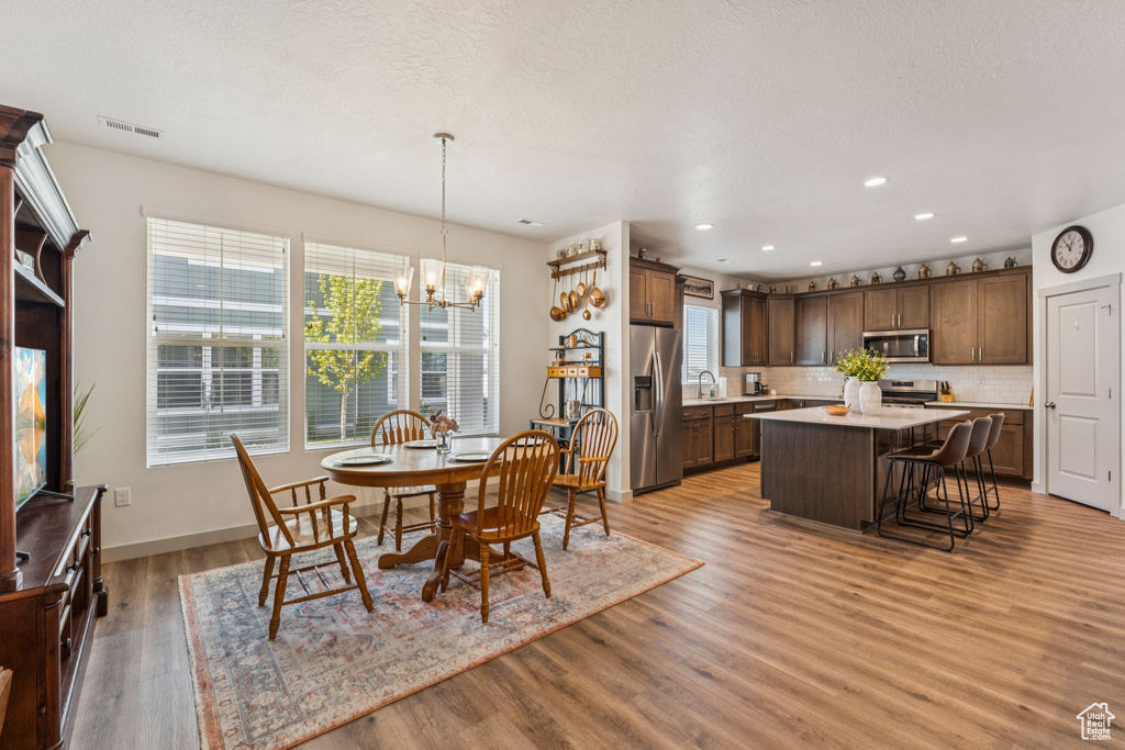 Dining space with a chandelier, plenty of natural light, light wood finished floors, and recessed lighting
