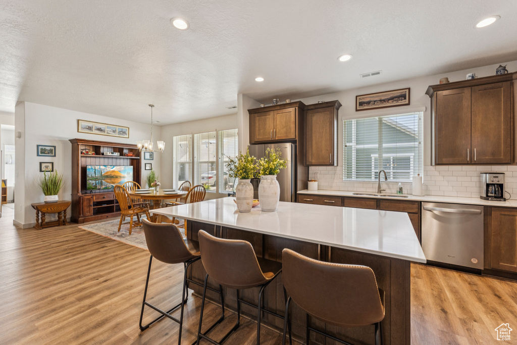 Kitchen featuring stainless steel appliances, light countertops, backsplash, light wood finished floors, and recessed lighting