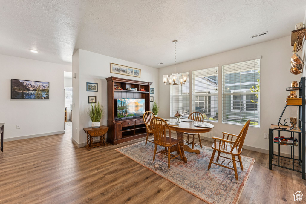 Dining space featuring wood finished floors, a chandelier, and a textured ceiling