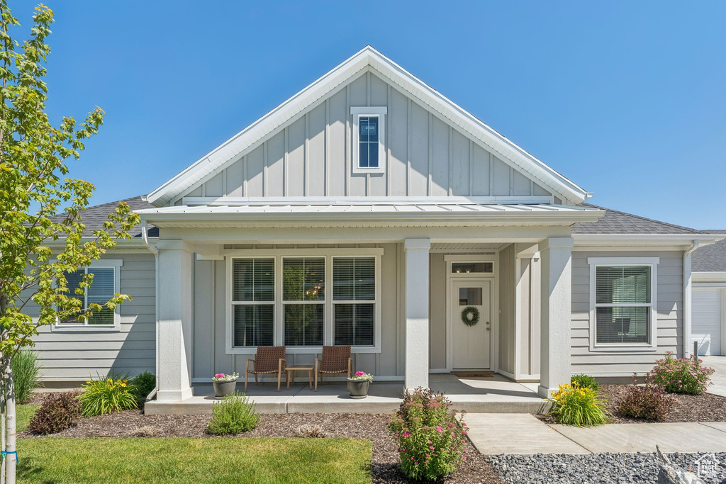 View of front of house with covered porch, board and batten siding, and a shingled roof
