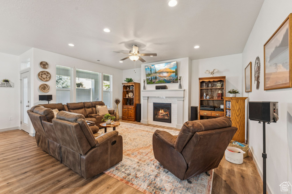 Living area featuring wood finished floors, a ceiling fan, a fireplace, and recessed lighting