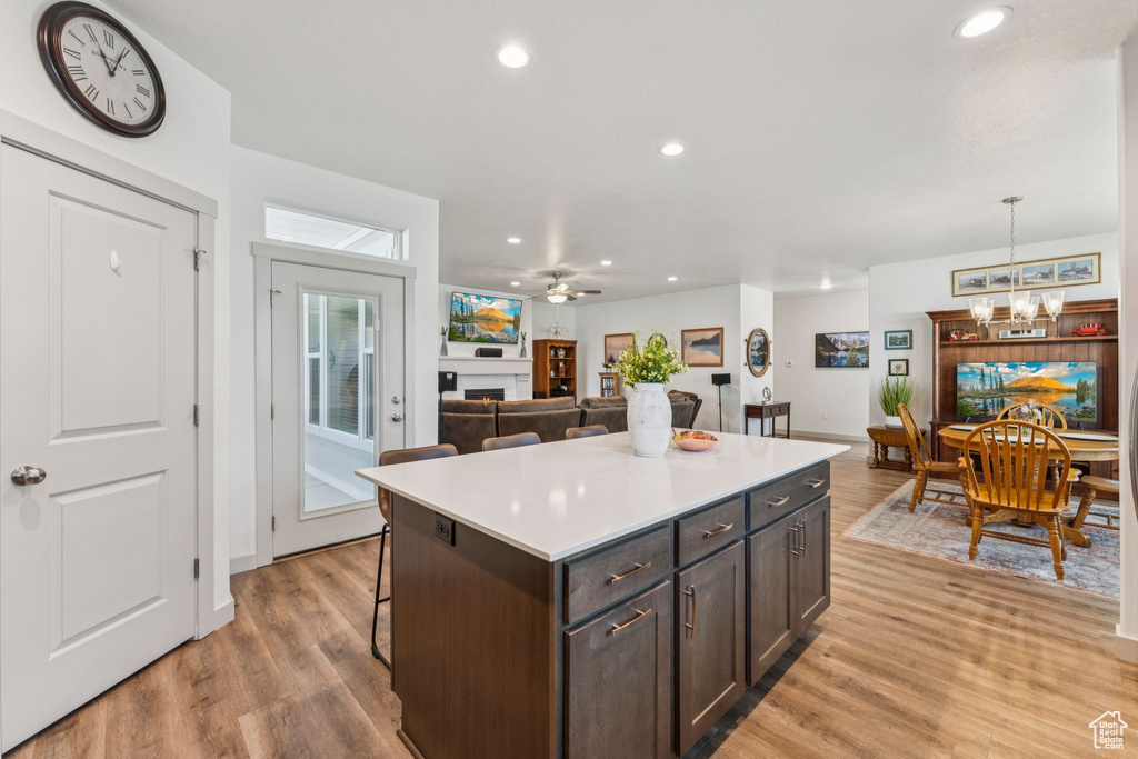 Kitchen with light wood-style flooring, a chandelier, a center island, a breakfast bar, and recessed lighting