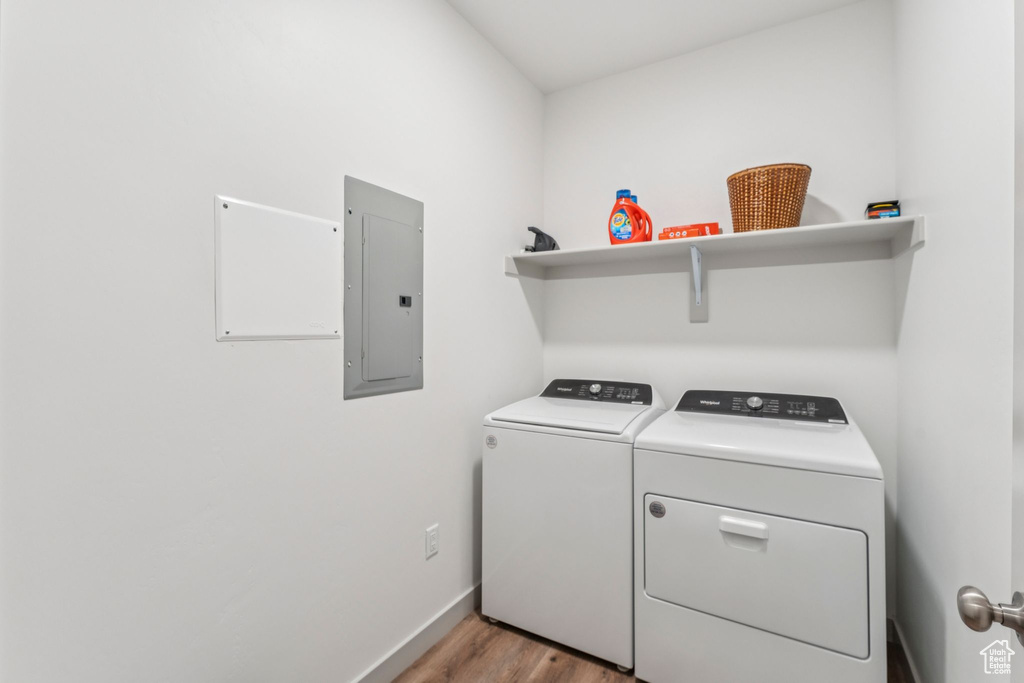 Laundry room featuring electric panel, washing machine and dryer, and light wood-style floors