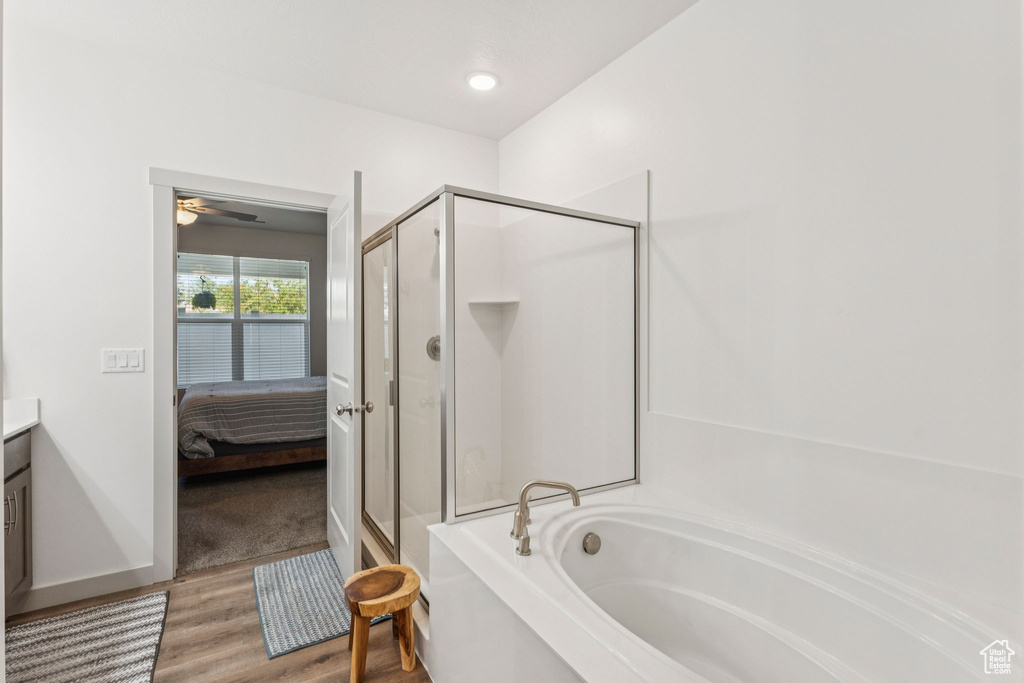 Ensuite bathroom with a stall shower, a bath, vanity, wood finished floors, and a ceiling fan