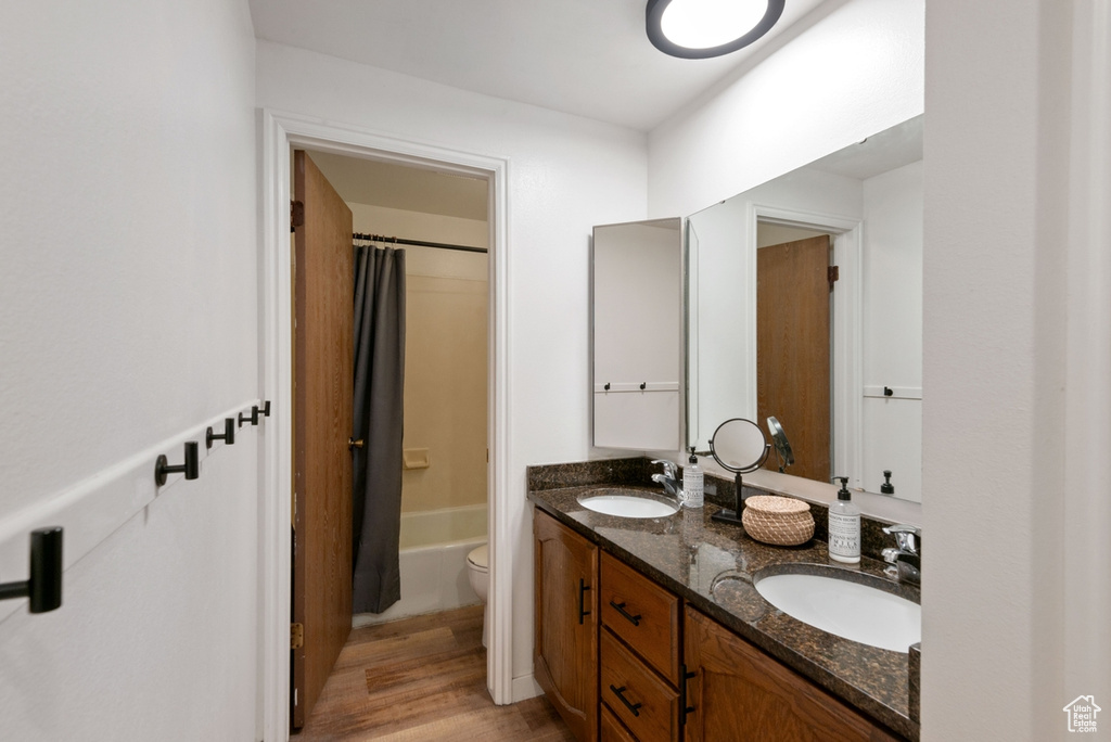 Full bath featuring double vanity, wood finished floors, and shower / bathtub combination with curtain