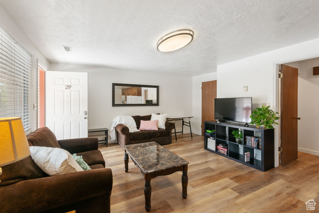 Living area with light wood-type flooring and a textured ceiling