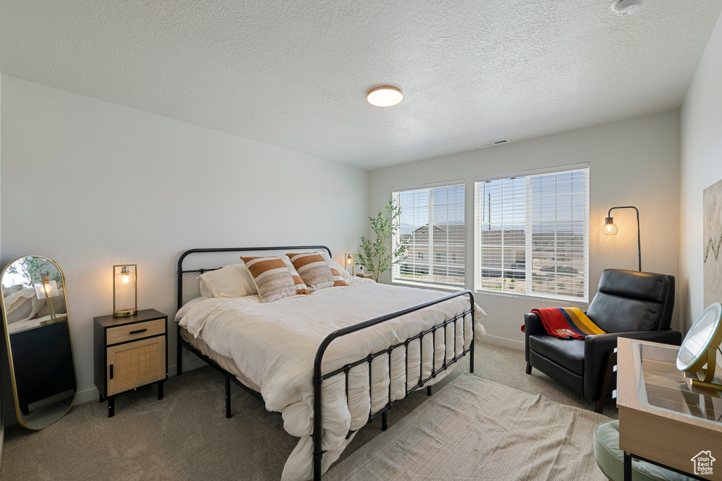 Bedroom with light colored carpet and a textured ceiling