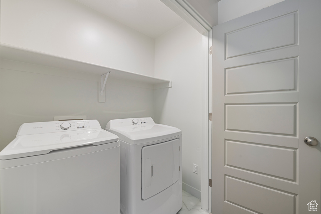 Laundry area with light marble finish floors and separate washer and dryer